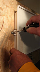 Person using a screwdriver to install a panel on wooden wall.